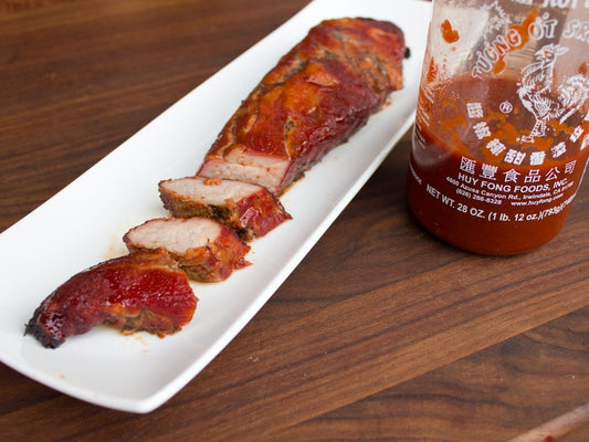 sliced spicy pork tenderloin and sriracha sauce bottle