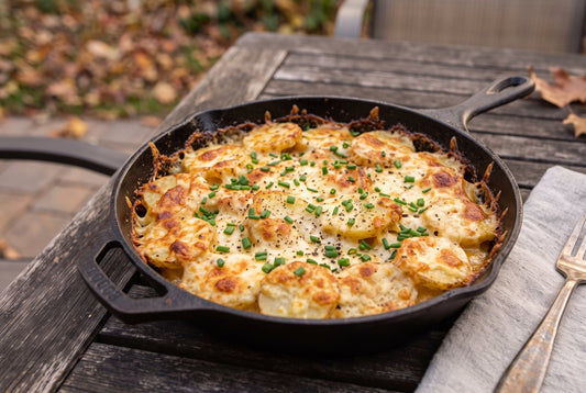 Smoked potato fennel gratin in a cast iron skillet cooked in a Bradley Smoker with bubbly golden Gruyère cheese